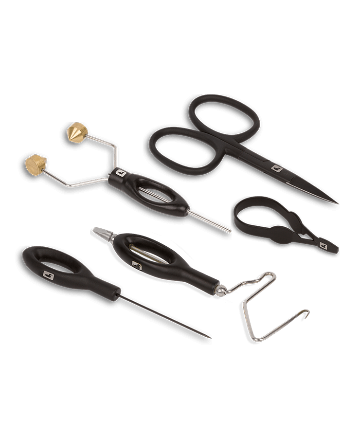 A beginner fly-tying tool kit laid out — ceramic bobbin, scissors, hackle pliers, bodkin, and a whip finisher